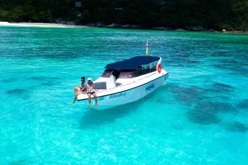 A boat gliding through crystal-clear blue waters near Coral Island, capturing the tranquility of a tropical escape.