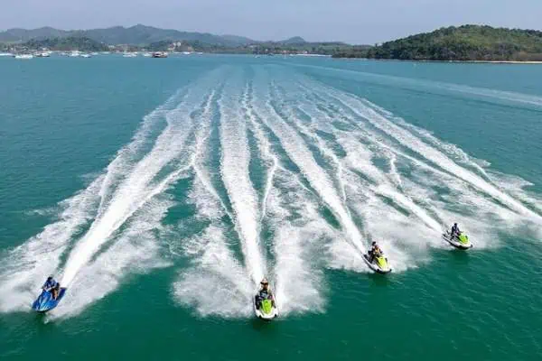 Several people riding jet skis on Phuket's vibrant blue ocean, showcasing excitement and adventure.