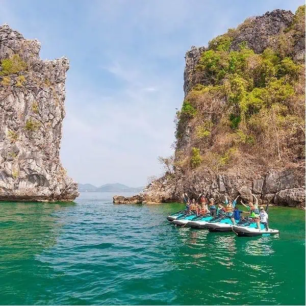 Group of individuals riding jet skis on Phuket's vibrant blue ocean, enjoying a sunny day.