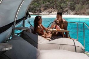 A couple shares a delightful meal together on a serene boat, surrounded by water and nature's beauty.