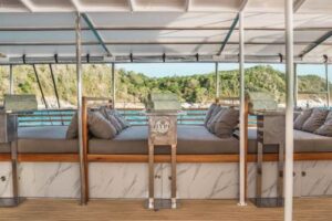 A cozy living room on a boat, featuring comfortable seating, nautical decor, and large windows showcasing the water view.