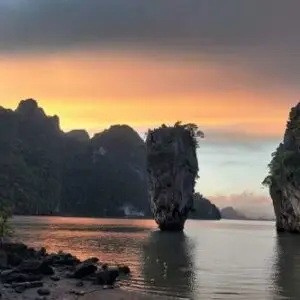 A serene sunset casting warm hues over the water, reflecting on the James Bond rocks in the foreground.