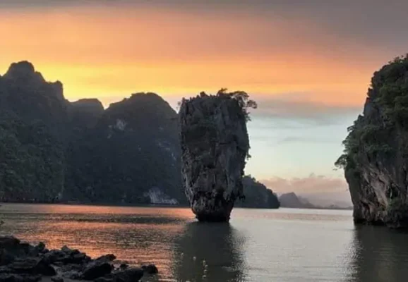 Ein ruhiger Sonnenuntergang, der warme Farbtöne über das Wasser wirft und sich an den James Bond Felsen im Vordergrund spiegelt.