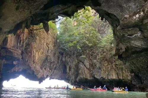 A person kayaking through the stunning caves of Krabi, surrounded by towering limestone cliffs and clear blue waters.