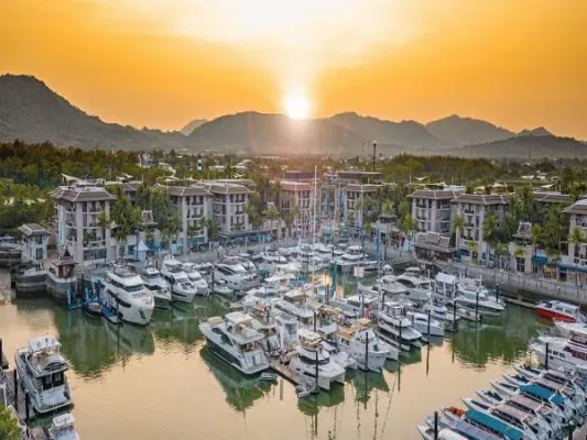 Die Sonne geht hinter dem Horizont unter und taucht eine Marina mit Booten in ein friedliches Licht, das die natürliche Schönheit der Szene betont. Perfekt für die Phuket Bootstour zu James Bond.