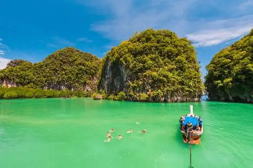 A longtail boat drifts peacefully in the vibrant turquoise waters of the island, embodying a tranquil tropical atmosphere.