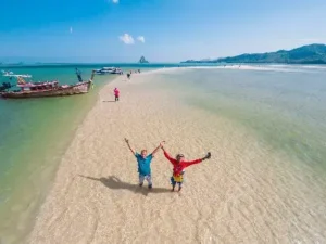 Two people celebrating on a pristine beach with a serene ocean view at Koh Yao.