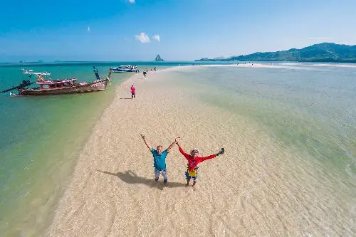 Two people celebrating on a pristine beach with a serene ocean view at Koh Yao.