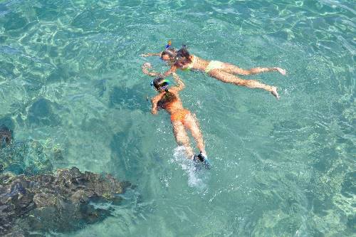 Two women engage in snorkeling in pristine water, discovering the beauty of underwater ecosystems.