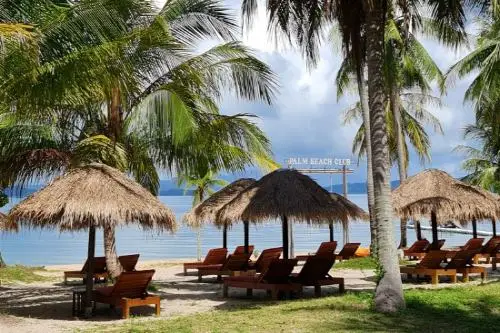 A picturesque beach with comfortable lounge chairs and thatched umbrellas, perfect for a day of leisure by the sea.