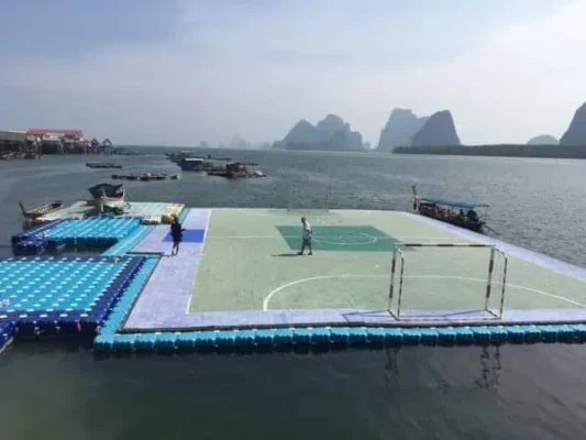 Ein lebendiges Fußballfeld, das auf dem Wasser bei Koh Panyee schwebt, mit Spielern in einem energischen Match unter klarem Himmel.