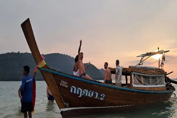 A Longtailboot gently floating on the water during a serene sunset, with warm hues illuminating the peaceful scene.