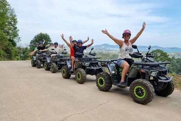 Vier Personen fahren mit ATVs auf einer malerischen Dschungelstraße und erleben den Nervenkitzel und die Schönheit eines Outdoor-Abenteuers.