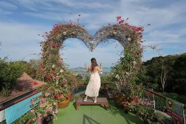 Eine Frau in Weiß steht auf einer Brücke, umgeben von blühenden Blumen, und genießt einen friedlichen Moment voller natürlicher Schönheit.