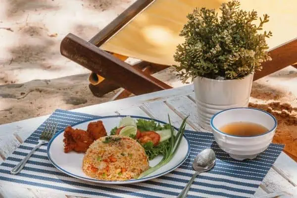 A plate of appetizing food on a beach chair, set against a peaceful beach with gentle ocean waves.