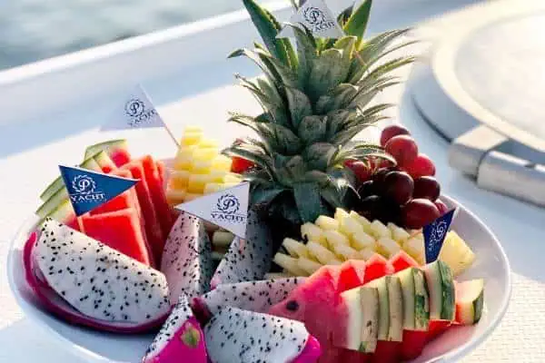 A vibrant catamaran with a bowl of fresh fruit and colorful flags, creating a festive and picturesque maritime ambiance for a Coral Island tour.