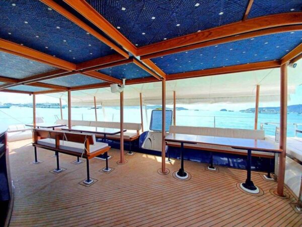 Interior of a boat featuring tables and chairs arranged for dining and relaxation.