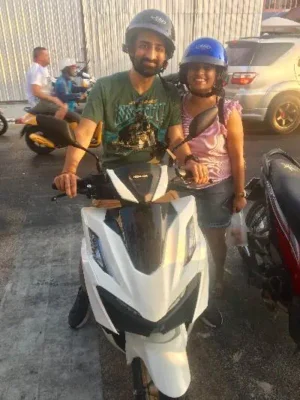 A man and woman renting a motorbike and enjoying a scenic outdoor adventure.