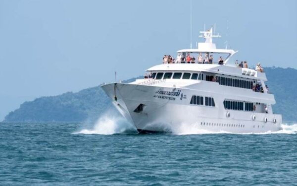 A large white boat navigates through the deep blue ocean waters under a clear sky.