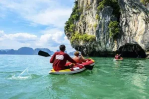 Sea Cave Canoeing at Talu Island: Tourists kayaking through the sea caves of Talu Island in Phang Nga Bay, surrounded by natural beauty.
