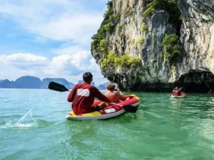 Sea Cave Canoeing at Talu Island: Tourists kayaking through the sea caves of Talu Island in Phang Nga Bay, surrounded by natural beauty.
