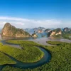 Traditionelles Longtail-Boot mit Passagieren auf einem ruhigen Fluss in der Phang Nga Bucht