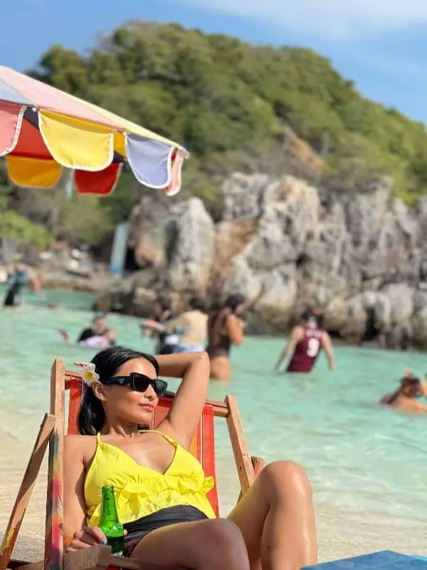 Frau in gelbem Bikini entspannt auf einer Strandliege an Khai Island, genießt Sonne und tropische Atmosphäre.