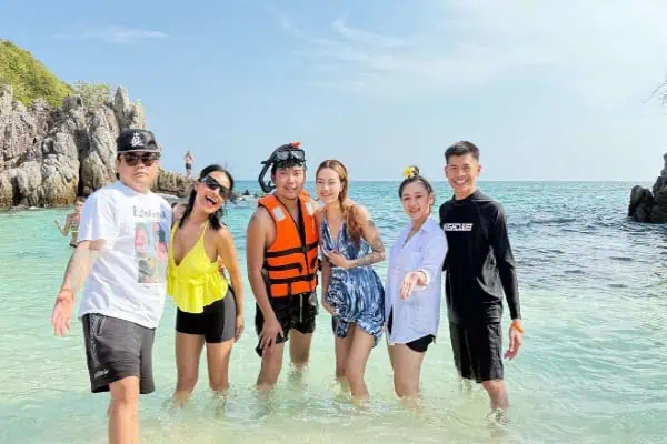 Happy travelers posing in the shallow turquoise waters of Khai Island for a memorable vacation photo.