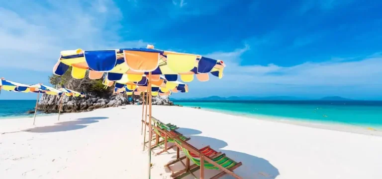 Weißer Sandstrand von Khai Nai Island mit kristallklarem Wasser und einer malerischen Kulisse aus Kalksteinfelsen.