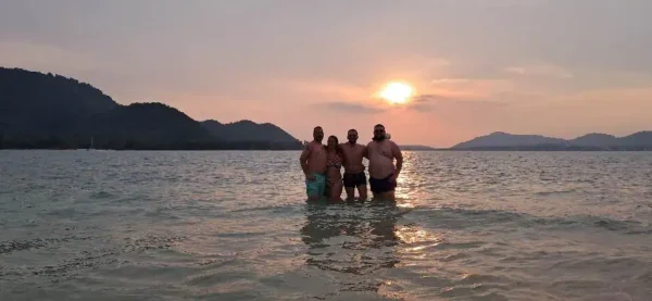 Menschen stehen im Wasser bei Sonnenuntergang, goldene Strahlen erleuchten die friedliche Landschaft.