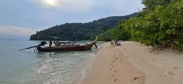 Boot am sandigen Strand, umgeben von tropischem Wald und üppigem Grün.