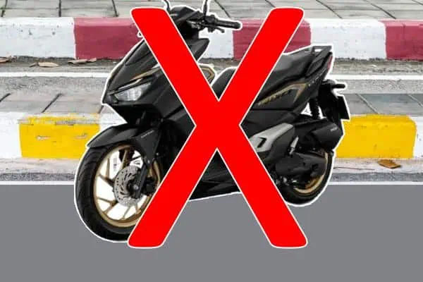 Motorbike parked illegally in front of red-and-white curb in Thailand