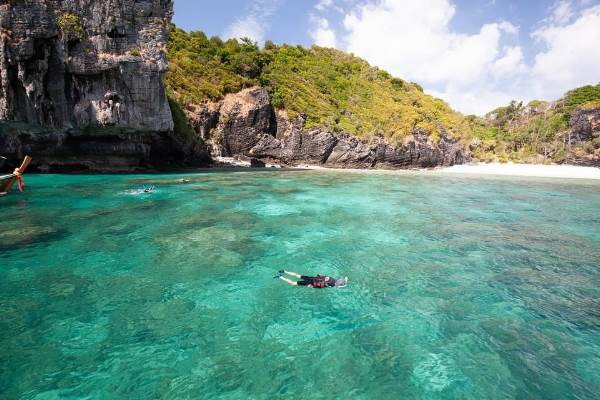 A man immersed in snorkeling within the clear waters of a tropical island, discovering the beauty of underwater life.