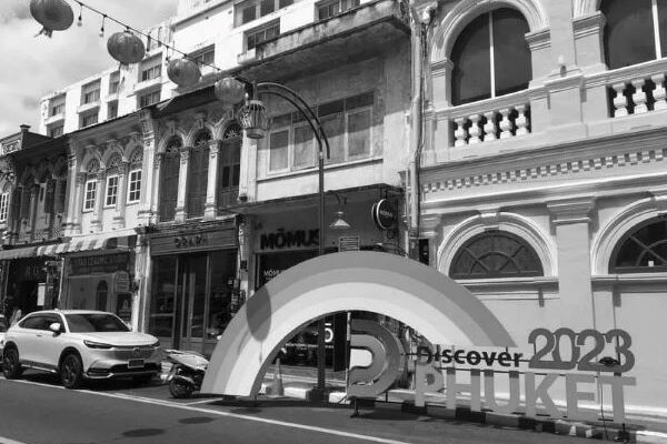 A black and white street scene featuring a prominent rainbow sign, symbolizing diversity and inclusivity.