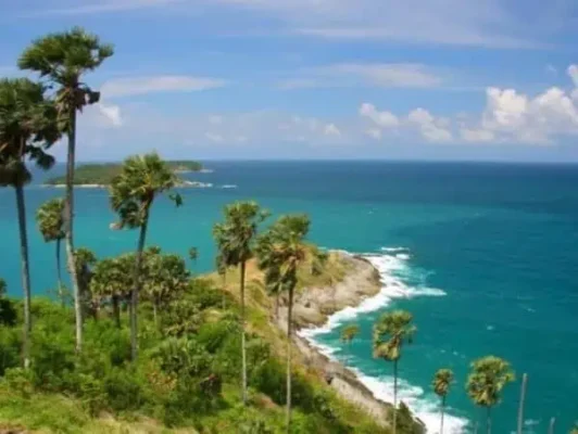 A breathtaking panoramic view from a hilltop, offering a vast ocean stretching to the horizon under a clear blue sky in Phuket.