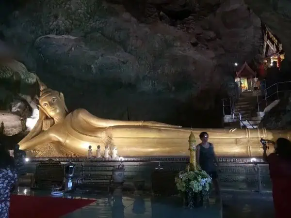 A large golden Buddha statue sits peacefully in a serene cave, emanating tranquility and spiritual energy.