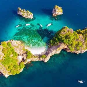 Aerial perspective of a small island showcasing vibrant green rocks amidst the surrounding ocean.