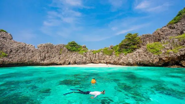 A man snorkeling in the clear turquoise waters of Rok Haa Island, surrounded by colorful marine life.