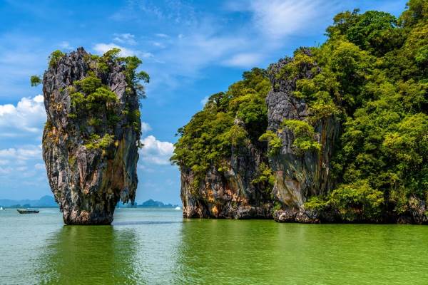 A serene view of Phang Nga Bay in Thailand, showcasing limestone cliffs and emerald waters under a clear blue sky.