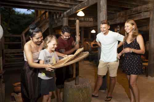 A family of four gathers around a wooden table, smiling and enjoying each other's company in a warm, inviting setting.