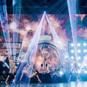 A vibrant stage at the Simon Cabaret Show in Phuket, featuring dancers illuminated by colorful lights.