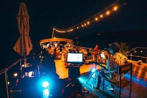 A man playing music on a boat at night, with soft lights reflecting on the water, creating a romantic atmosphere perfect for a sunset cruise.