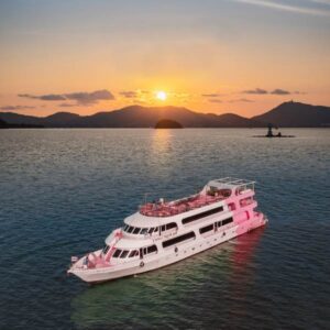 A pink and white boat is seen floating in the ocean, creating a picturesque scene against the blue water.