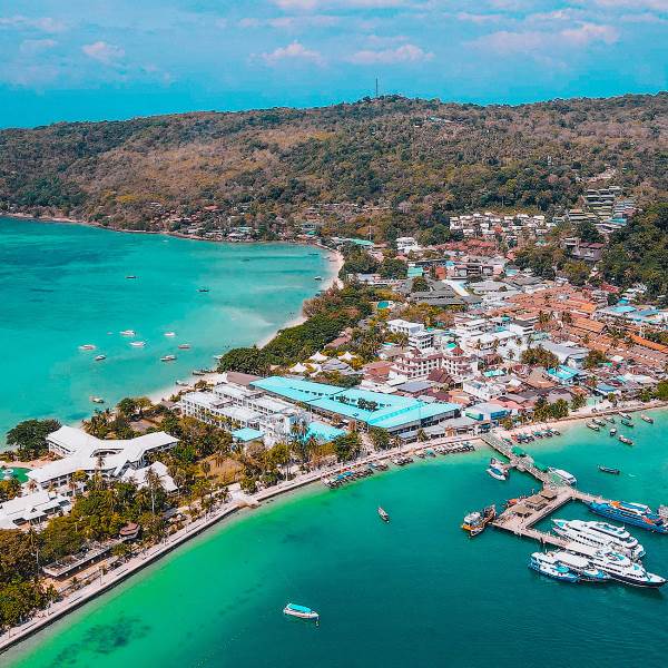 Aerial view of a tropical beach and town, emphasizing the beauty of the coastline and lush tropical environment.