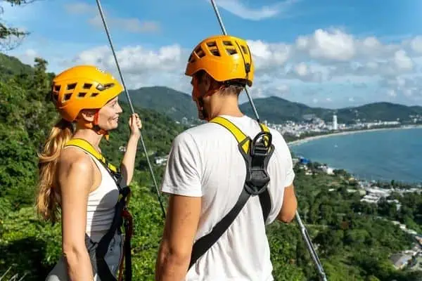 Paar gleitet auf einer Zipline durch eine atemberaubende Berglandschaft in Phuket und genießt Abenteuer und Verbundenheit.