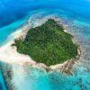 An island encircled by vibrant blue waters and lush green trees, showcasing a serene natural landscape.