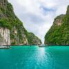 Boats gently bob in the turquoise waters of a serene bay, surrounded by a picturesque coastal landscape.