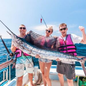 Three individuals in life jackets proudly display a sailfish they have caught, showcasing their successful fishing adventure