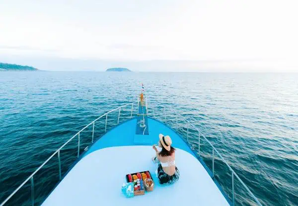 Eine Frau sitzt ruhig auf dem Deck eines Bootes und genießt den friedlichen Blick auf das umgebende Wasser und die Landschaft während einer ruhigen Bootsfahrt.