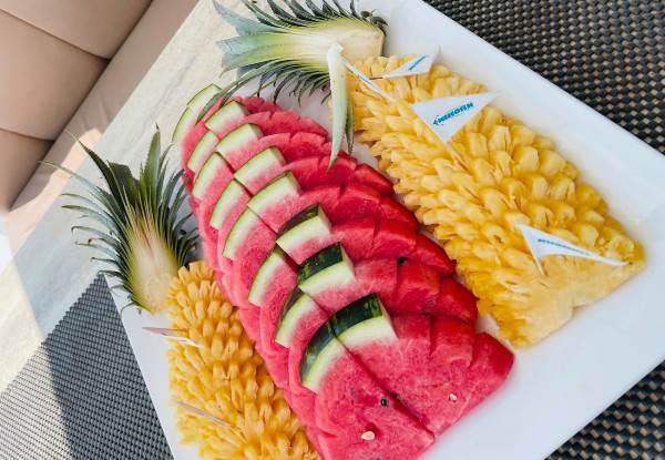 A vibrant plate of assorted fruits artistically arranged to resemble the shape of a pineapple.